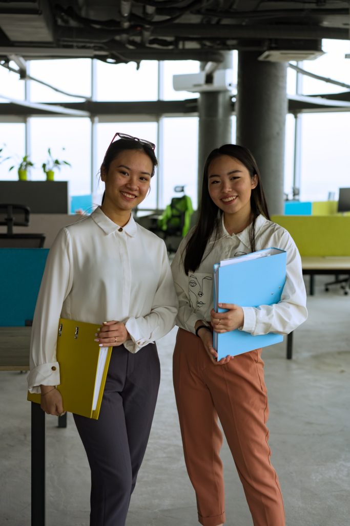 two women standing with notebooks